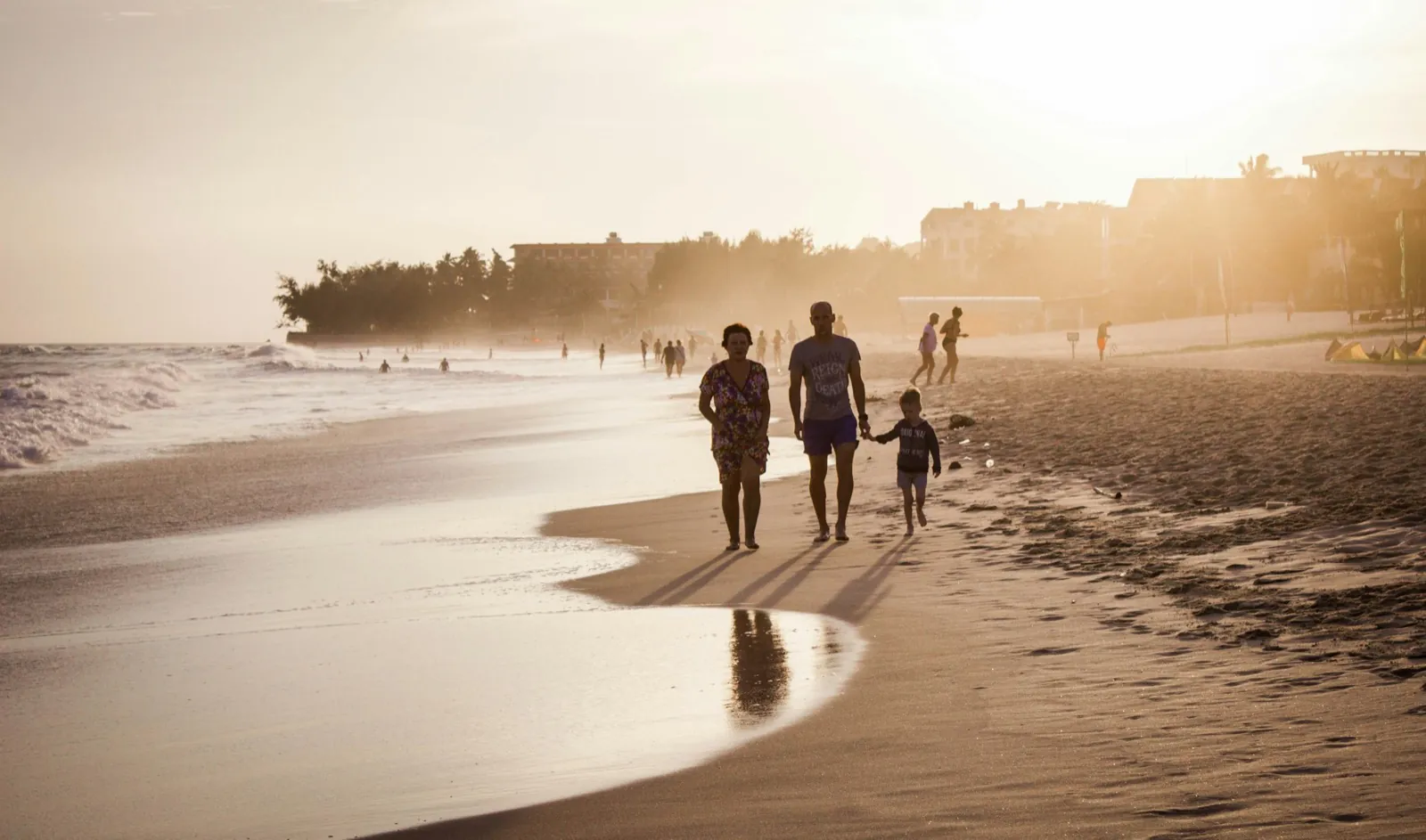 A family walking along the shoreline at golden hour