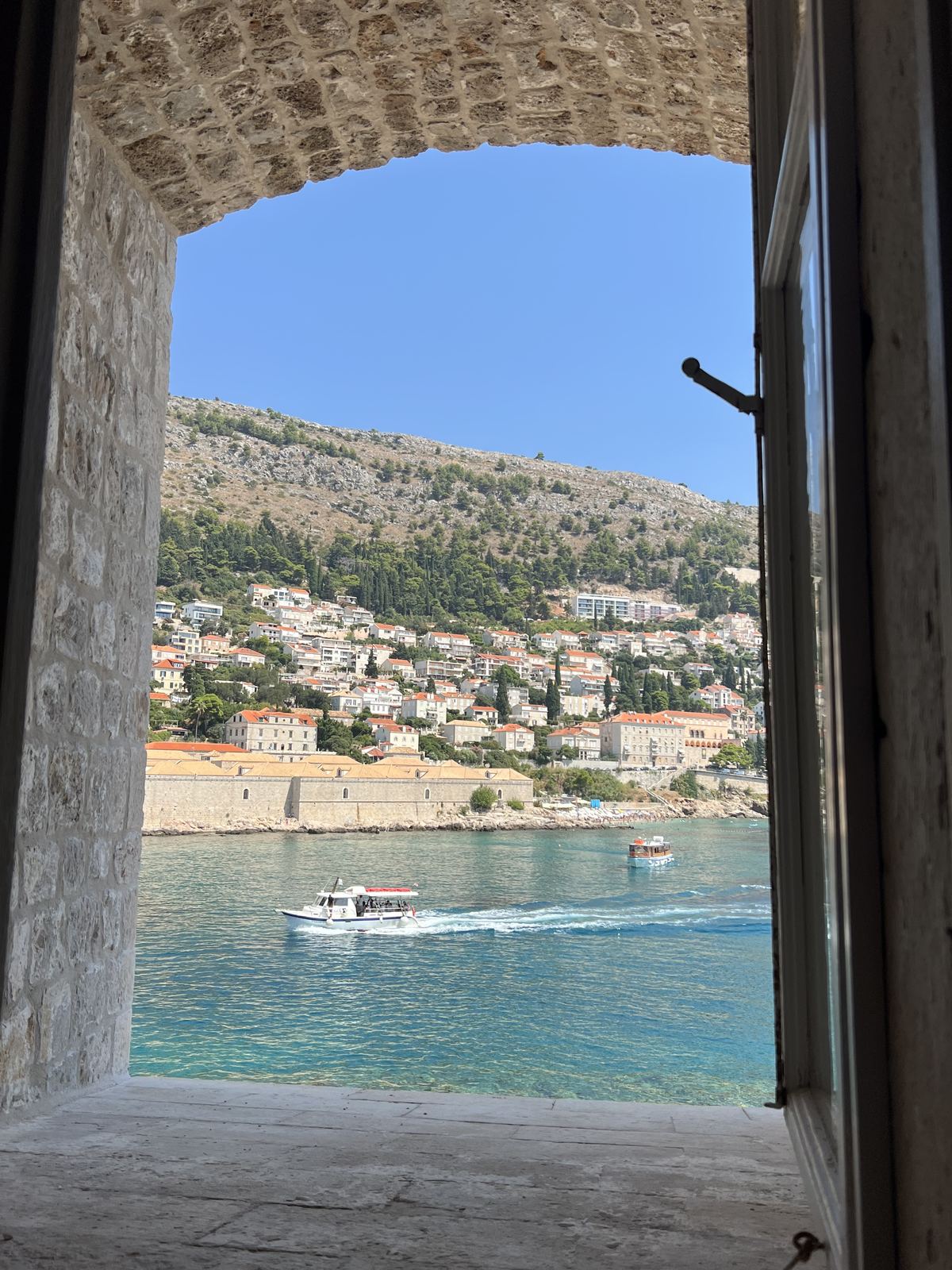 A boat on the Adriatic, framed by a stone window in the Dubrovnik city walls