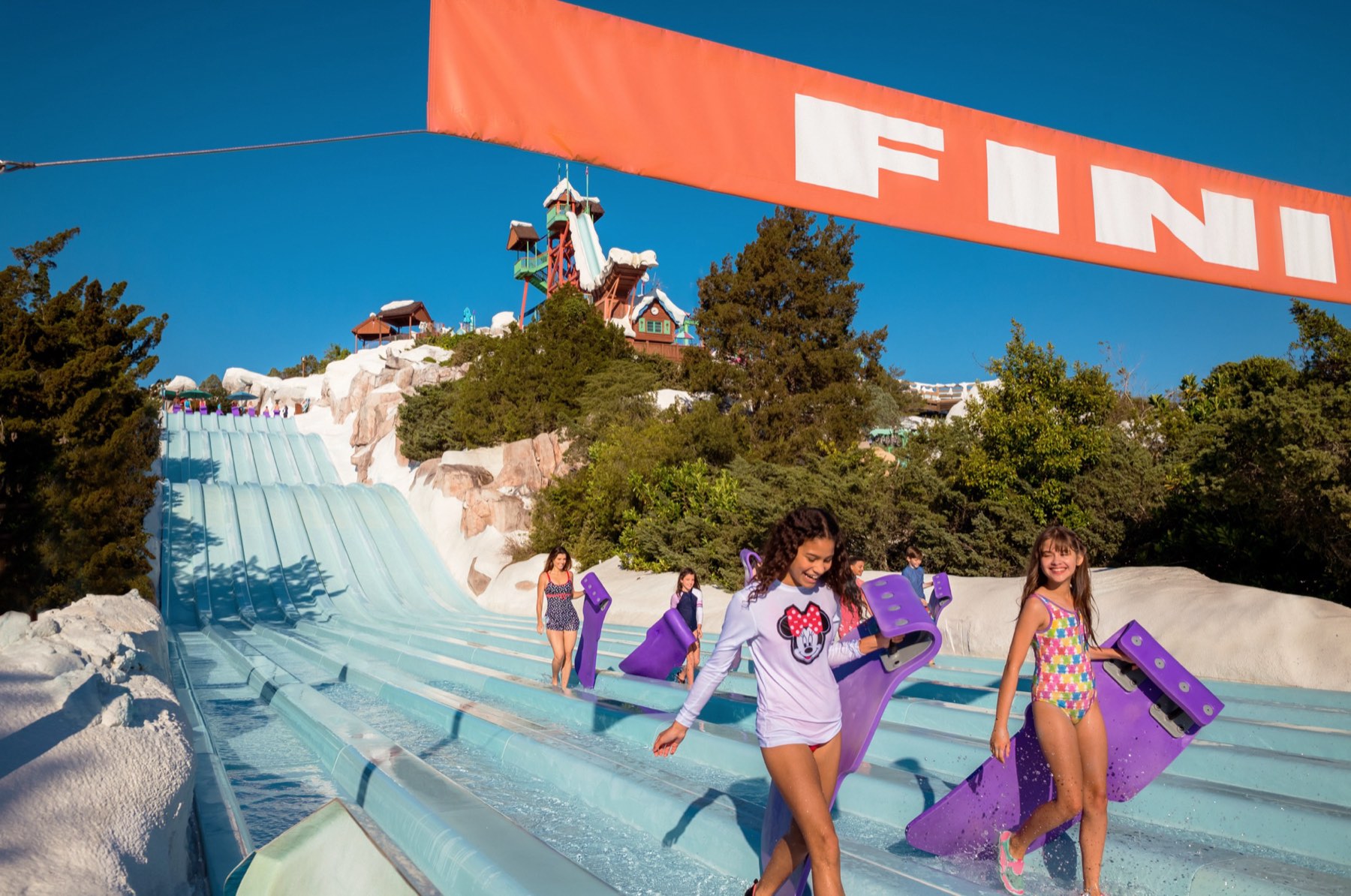 Kids carrying mats away from the finish line of a slide at Disney's Blizzard Beach Water Park