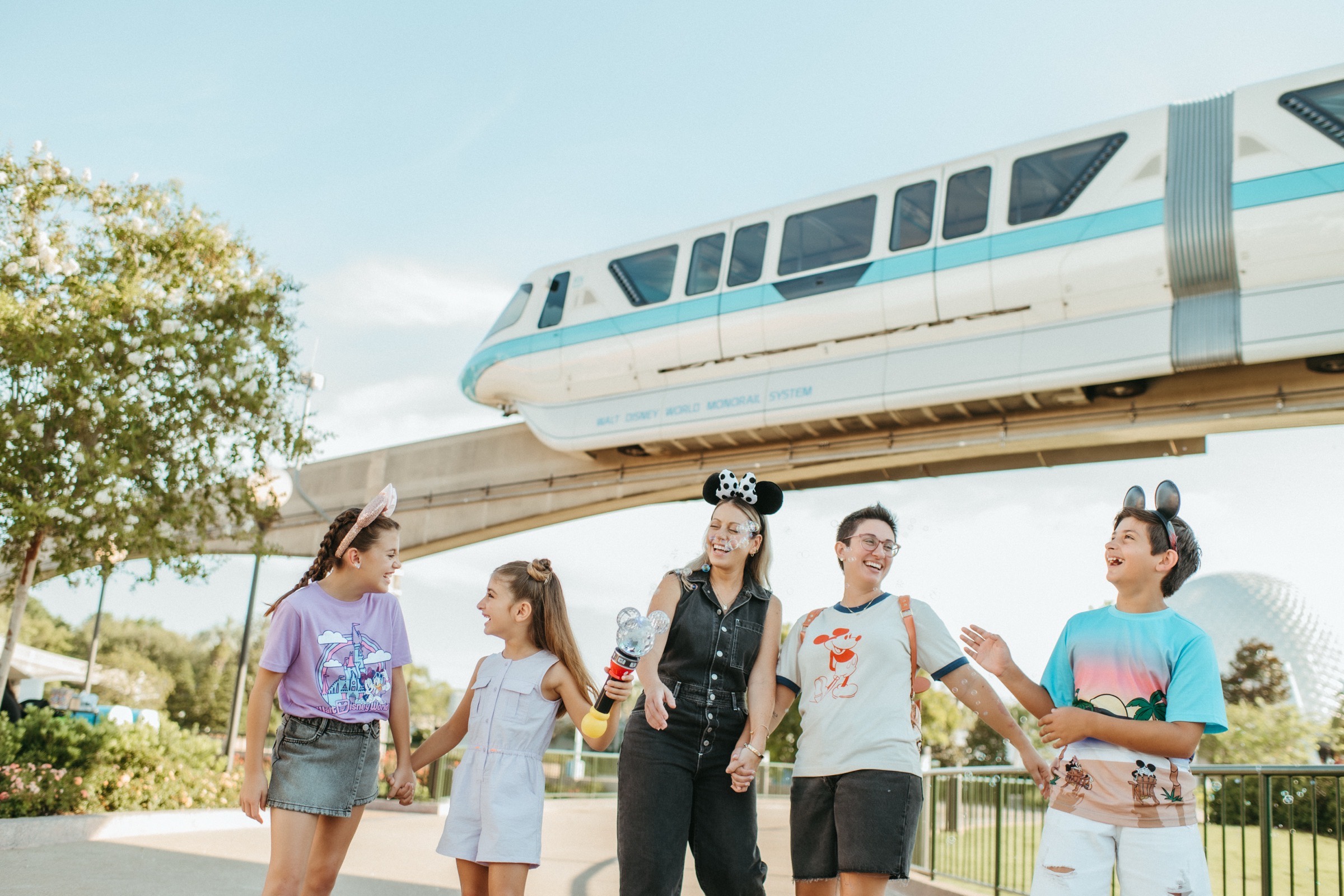 A family walking beneath the Walt Disney World Monorail at EPCOT